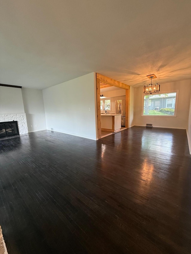 123 Birchridge Dr, Brainerd, MN 56401 - unfurnished living room with wood finished floors, a chandelier, a fireplace, and baseboards
