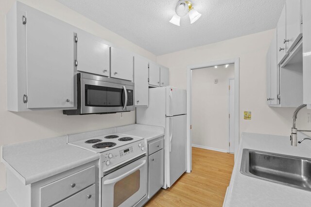 10113 34th St Unit 105, Minnetonka, MN 55305 - kitchen with white appliances, a sink, light countertops, light wood finished floors, and a textured ceiling