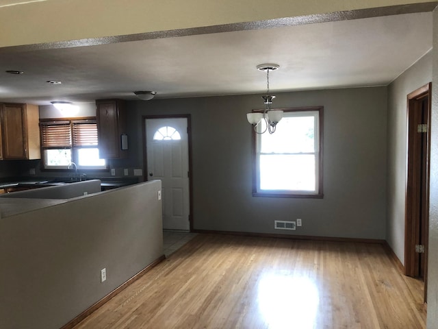 1304 13th Ave N, Moorhead, MN 56560 - kitchen featuring light wood-style flooring, a chandelier, baseboards, pendant lighting, and dark countertops