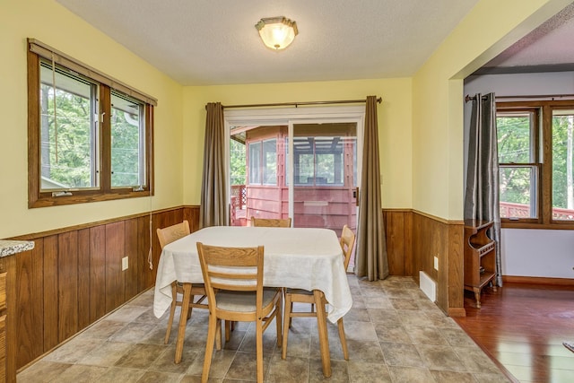 1357 64th Ave NE, Fridley, MN 55432 - dining room with wainscoting, wooden walls, plenty of natural light, a textured ceiling, and stone finish floors