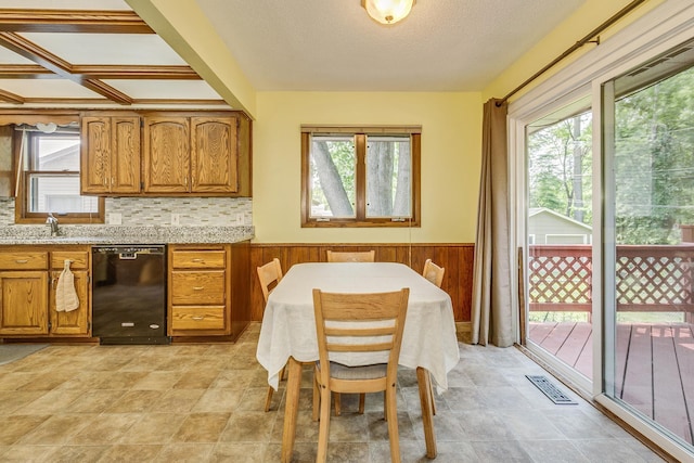 1357 64th Ave NE, Fridley, MN 55432 - kitchen featuring dishwasher, healthy amount of natural light, brown cabinets, a wainscoted wall, and wood walls