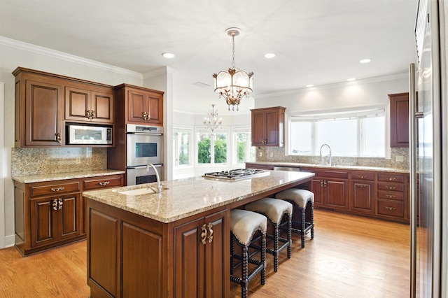 2645 Arcola Ln, Minnetonka Beach, MN 55391 - kitchen featuring appliances with stainless steel finishes, a chandelier, an island with sink, light wood-style floors, and backsplash
