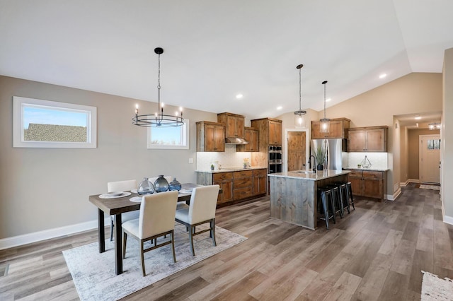 10014 177th Ave NW, Elk River, MN 55330 - dining room with vaulted ceiling, light wood finished floors, a chandelier, and baseboards
