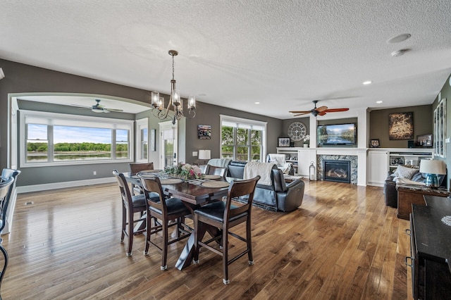 26042 Sunset Dr, Chisago City, MN 55013 - dining room with ceiling fan, a textured ceiling, wood finished floors, arched walkways, and a glass covered fireplace