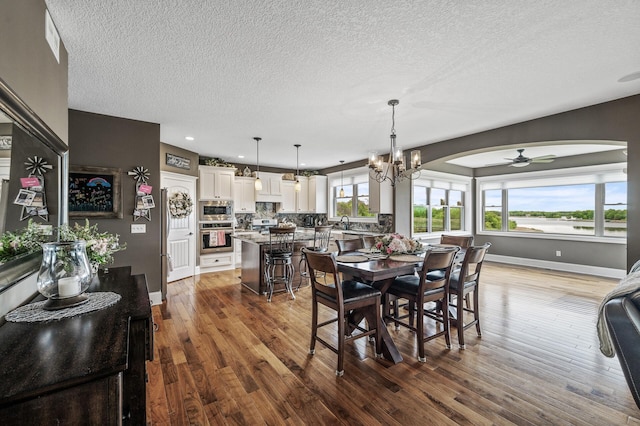 26042 Sunset Dr, Chisago City, MN 55013 - dining space featuring a textured ceiling, wood finished floors, arched walkways, a ceiling fan, and baseboards