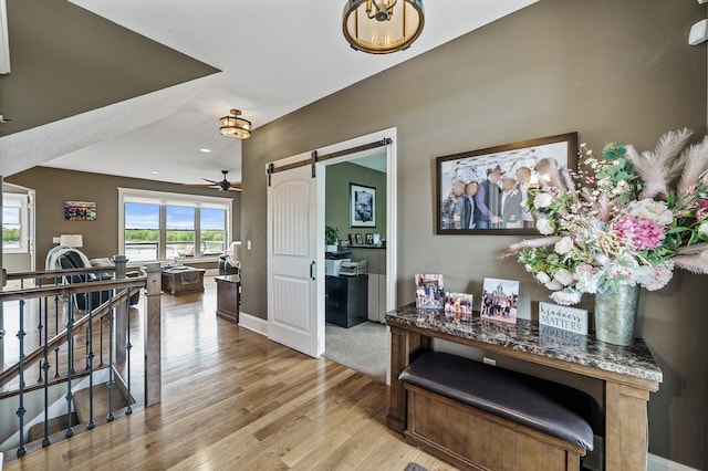 26042 Sunset Dr, Chisago City, MN 55013 - hall with light wood finished floors, a barn door, baseboards, recessed lighting, and an upstairs landing