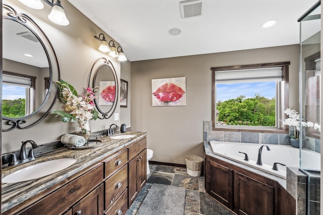 26042 Sunset Dr, Chisago City, MN 55013 - bathroom featuring stone tile flooring, double vanity, a garden tub, toilet, and baseboards