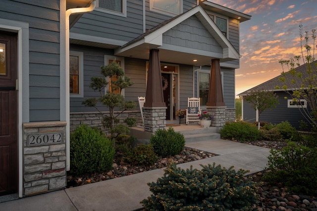 26042 Sunset Dr, Chisago City, MN 55013 - exterior entry at dusk with covered porch and stone siding