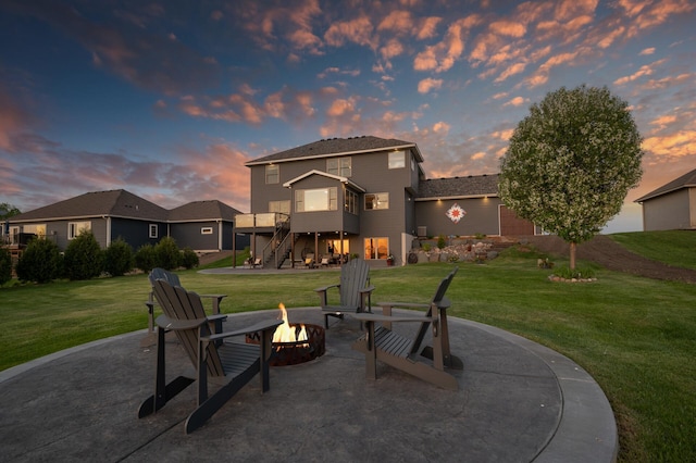 26042 Sunset Dr, Chisago City, MN 55013 - patio terrace at dusk with an outdoor fire pit, stairway, a lawn, and a patio