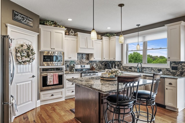 26042 Sunset Dr, Chisago City, MN 55013 - kitchen featuring stainless steel appliances, a kitchen breakfast bar, dark stone countertops, backsplash, and a center island