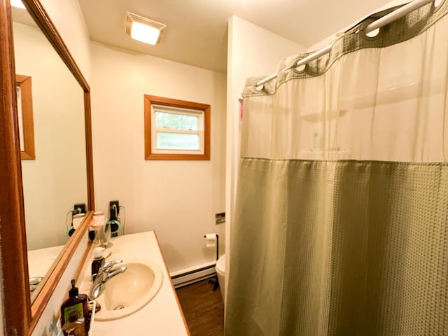 408 Lafayette Ave, Fulda, MN 56131 - bathroom featuring toilet, a baseboard heating unit, vanity, wood finished floors, and a shower with curtain