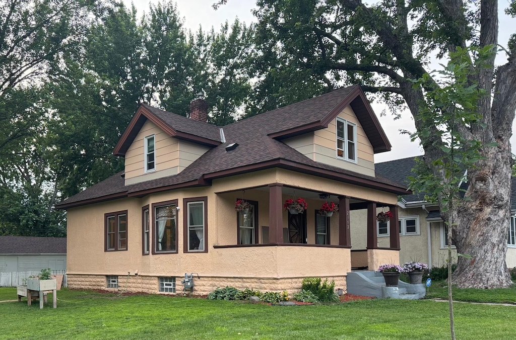2852 36th Ave S, Minneapolis, MN 55406 - view of front of house featuring roof with shingles, a front yard, a chimney, a porch, and stucco siding