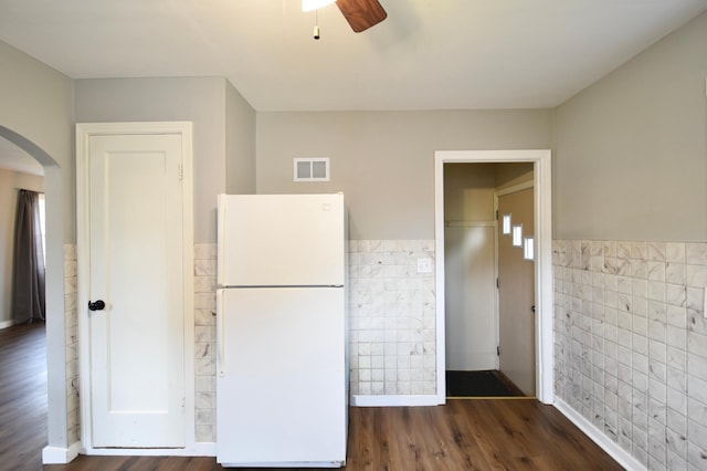 705 1st Ave SE, Pine Island, MN 55963 - kitchen featuring freestanding refrigerator, tile walls, arched walkways, ceiling fan, and dark wood-style flooring