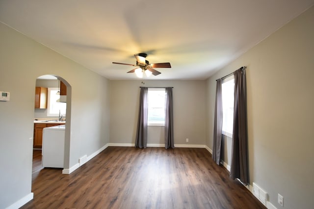 705 1st Ave SE, Pine Island, MN 55963 - unfurnished room featuring arched walkways, ceiling fan, dark wood-style flooring, and baseboards