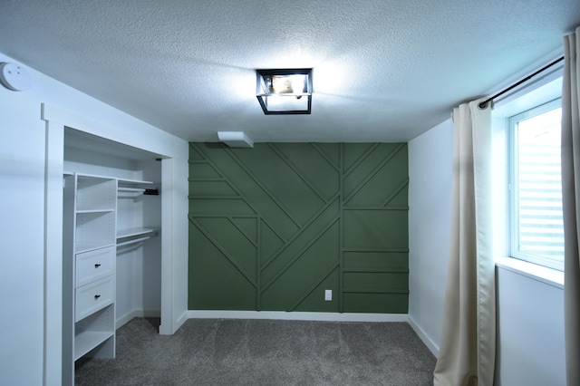 705 1st Ave SE, Pine Island, MN 55963 - unfurnished bedroom featuring dark carpet, a decorative wall, a textured ceiling, baseboards, and a closet