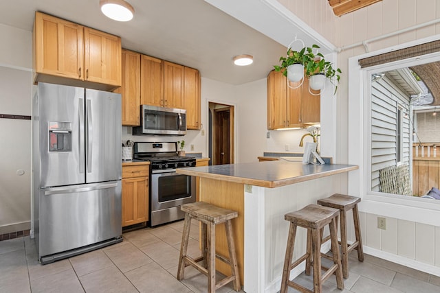 1391 Jefferson Ave, Saint Paul, MN 55105 - kitchen with appliances with stainless steel finishes, light tile patterned flooring, a breakfast bar area, and a sink