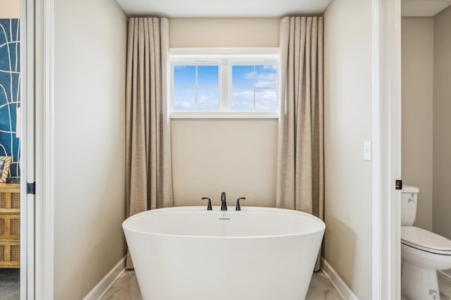 6601 Tamarack Ln, Corcoran, MN 55340 - bathroom featuring a freestanding bath, toilet, and baseboards