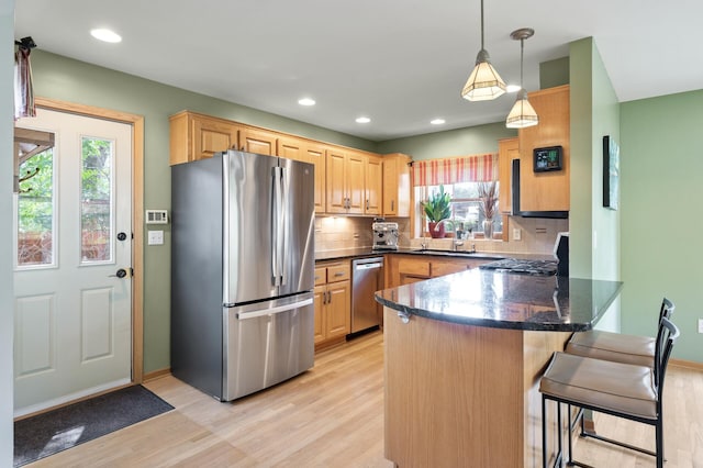 5136 16th Ave S, Minneapolis, MN 55417 - kitchen with appliances with stainless steel finishes, a peninsula, light wood-type flooring, tasteful backsplash, and a sink