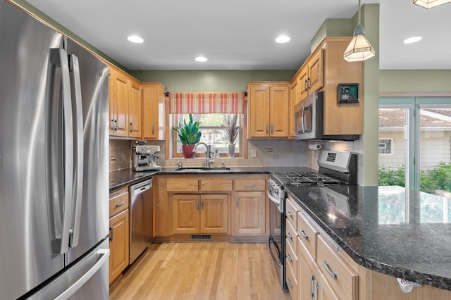 5136 16th Ave S, Minneapolis, MN 55417 - kitchen with stainless steel appliances, a sink, light wood-style flooring, tasteful backsplash, and dark stone counters