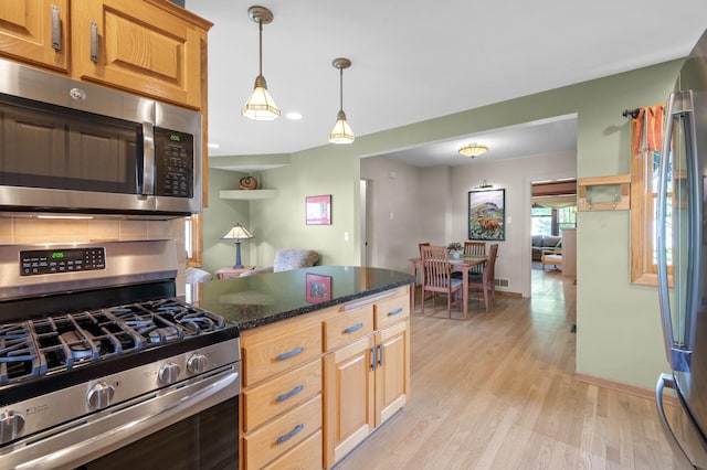 5136 16th Ave S, Minneapolis, MN 55417 - kitchen featuring appliances with stainless steel finishes, light wood finished floors, dark stone counters, hanging light fixtures, and baseboards