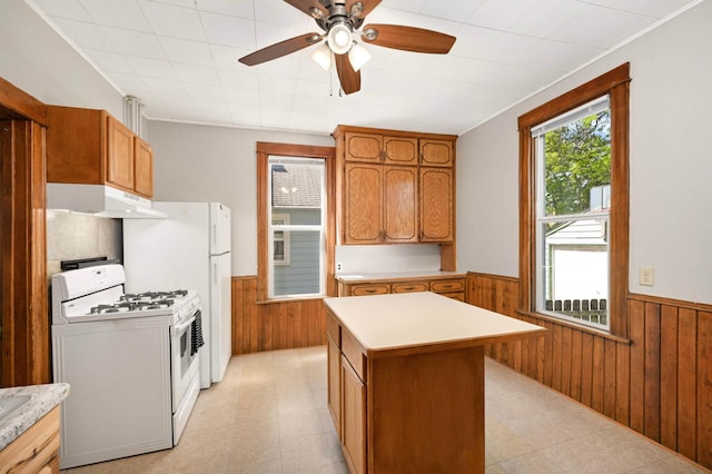 857 Oakdale Ave, Saint Paul, MN 55107 - kitchen featuring white range with gas cooktop, a wainscoted wall, wood walls, under cabinet range hood, and light countertops