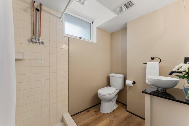 713 9th St NW, Buffalo, MN 55313 - full bath featuring wood finished floors, tiled shower, toilet, and vanity