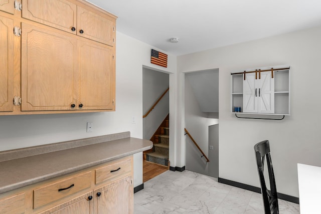 713 9th St NW, Buffalo, MN 55313 - kitchen featuring light marble finish floors, light brown cabinetry, and baseboards