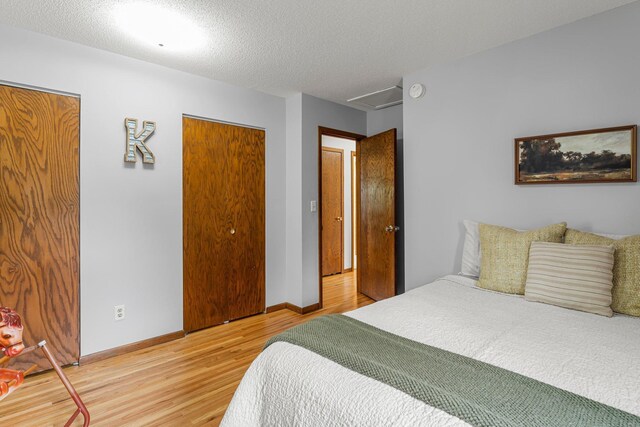 713 9th St NW, Buffalo, MN 55313 - bedroom featuring attic access, light wood-type flooring, baseboards, and a textured ceiling