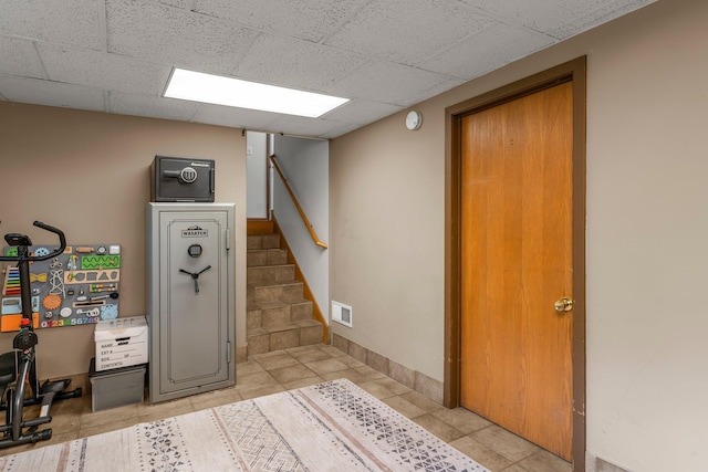 713 9th St NW, Buffalo, MN 55313 - finished basement with stairs, light tile patterned floors, and a paneled ceiling