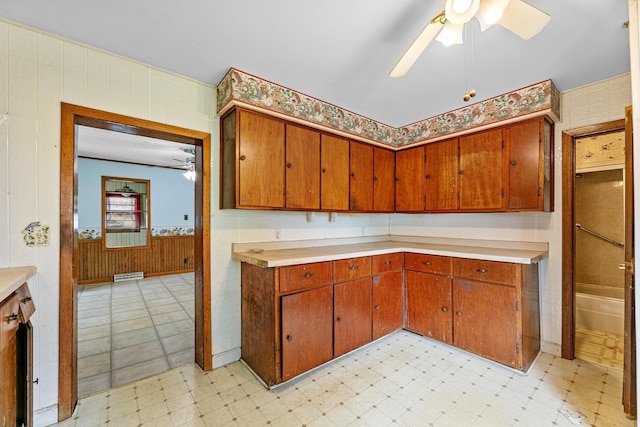909 14th St S, Benson, MN 56215 - kitchen with a ceiling fan, light flooring, brown cabinetry, and a wainscoted wall