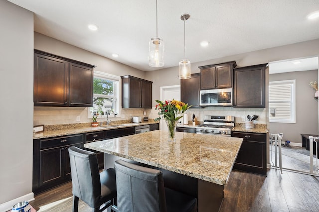 4847 Ashton Curv, Woodbury, MN 55129 - kitchen featuring stainless steel appliances, a sink, a center island, decorative backsplash, and dark brown cabinets
