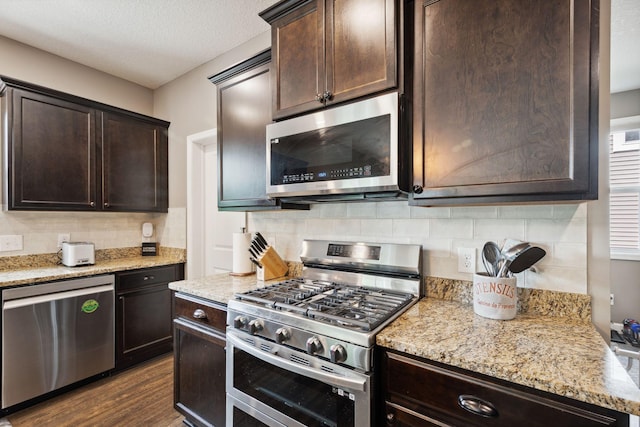4847 Ashton Curv, Woodbury, MN 55129 - kitchen featuring appliances with stainless steel finishes, dark brown cabinetry, backsplash, dark wood-style floors, and light stone counters