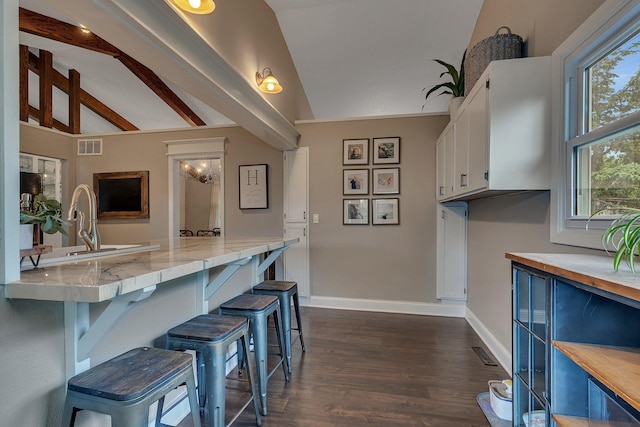 1276 13th Ave N, Saint Cloud, MN 56303 - kitchen featuring light countertops, white cabinetry, a kitchen bar, dark wood-style flooring, and baseboards