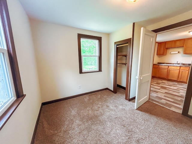 216 Main Ave S, New York Mills, MN 56567 - unfurnished bedroom with light carpet, a closet, a sink, and baseboards