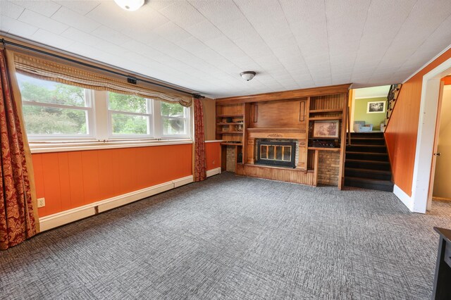 5851 Fairway Ln, Saint Cloud, MN 56303 - unfurnished living room featuring a glass covered fireplace, stairway, carpet, a baseboard heating unit, and wooden walls