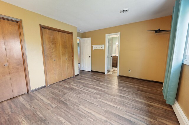 5851 Fairway Ln, Saint Cloud, MN 56303 - unfurnished bedroom featuring two closets, wood finished floors, and ensuite bath