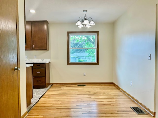 8212 15th Ave S, Bloomington, MN 55425 - unfurnished dining area featuring light wood finished floors, a chandelier, and baseboards