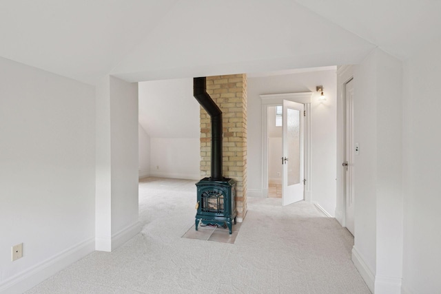 3252 Aldrich Ave S, Minneapolis, MN 55408 - unfurnished living room featuring a wood stove, carpet, vaulted ceiling, and baseboards