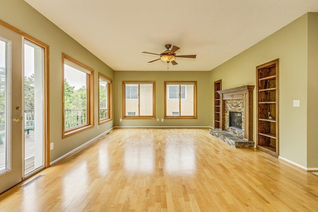 947 Dawn Ave, Shoreview, MN 55126 - unfurnished living room featuring light wood-style floors, a ceiling fan, baseboards, a stone fireplace, and built in shelves