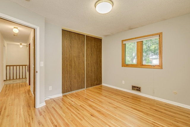 947 Dawn Ave, Shoreview, MN 55126 - unfurnished bedroom with light wood-style floors, a closet, baseboards, and a textured ceiling