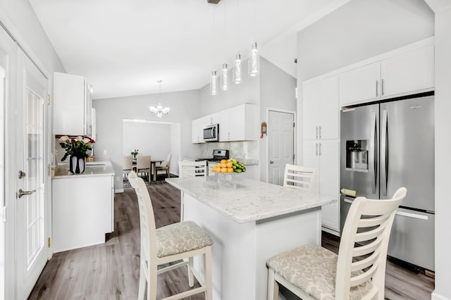 15710 Fox St NW, Andover, MN 55304 - kitchen featuring stainless steel appliances, wood finished floors, vaulted ceiling, white cabinetry, and a kitchen island