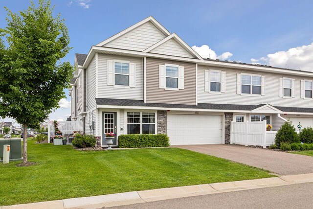 8061 Abercrombie Ln, Woodbury, MN 55129 - view of property featuring asphalt driveway, stone siding, a garage, and a front lawn