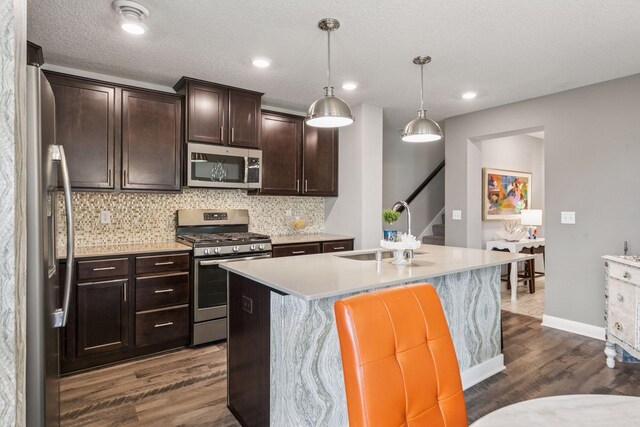 8061 Abercrombie Ln, Woodbury, MN 55129 - kitchen featuring stainless steel appliances, a sink, dark wood-style floors, a center island with sink, and light countertops