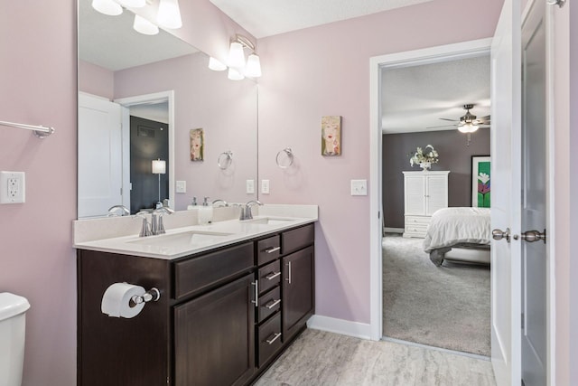 8061 Abercrombie Ln, Woodbury, MN 55129 - ensuite bathroom with double vanity, toilet, baseboards, ceiling fan, and wood finished floors