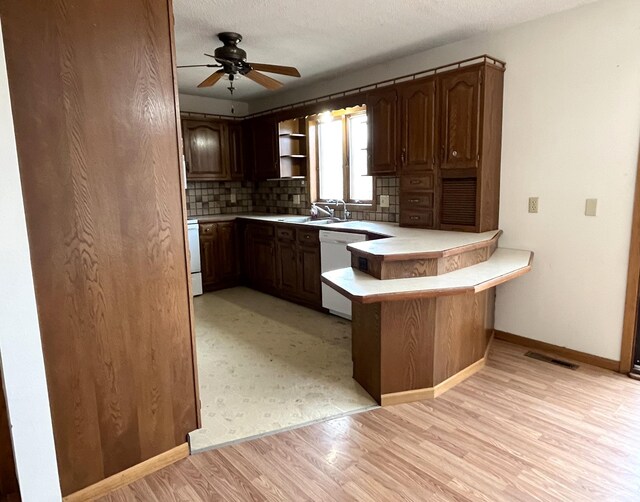 310 8th St, Windom, MN 56101 - kitchen featuring white dishwasher, light countertops, a peninsula, light wood-style floors, and a ceiling fan