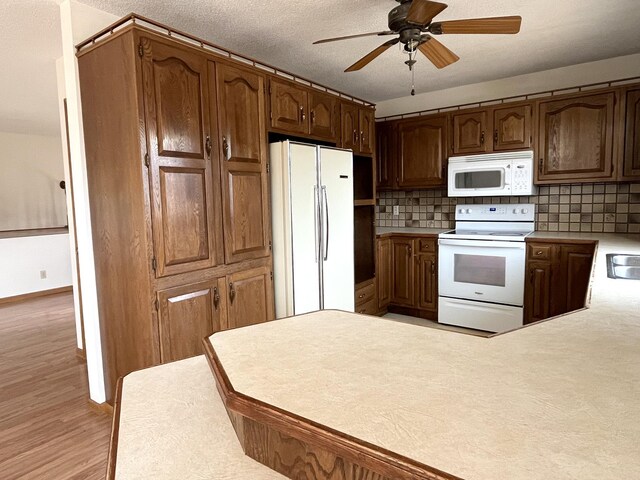 310 8th St, Windom, MN 56101 - kitchen featuring white appliances, ceiling fan, light countertops, decorative backsplash, and light wood finished floors