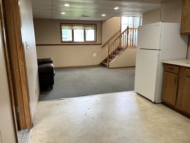 310 8th St, Windom, MN 56101 - basement featuring plenty of natural light, freestanding refrigerator, stairway, a drop ceiling, and light carpet
