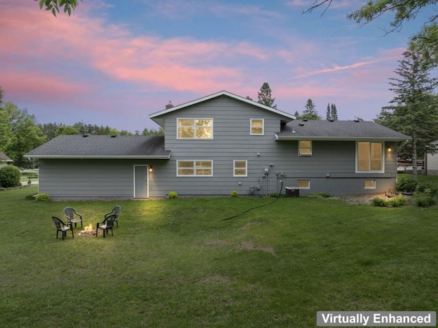 1719 Buckingham Path, Faribault, MN 55021 - back of property with an outdoor fire pit, a yard, a shingled roof, and central AC