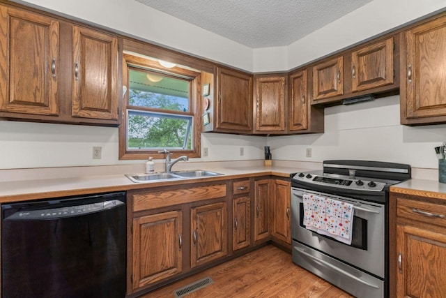 1719 Buckingham Path, Faribault, MN 55021 - kitchen with black dishwasher, stainless steel range with electric stovetop, a sink, brown cabinets, and light countertops