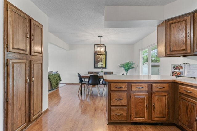 1719 Buckingham Path, Faribault, MN 55021 - kitchen with a peninsula, brown cabinetry, light wood-style flooring, and a textured ceiling
